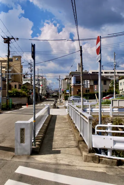 橋の欄干と進入禁止の標識の先に、電線と住宅の見える風景