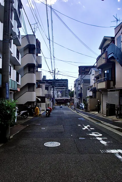 建物に挟まれたまっすぐな通りの奥を、電車が横切る風景