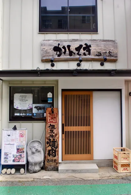 木の看板とたぬきの置物、格子戸が並ぶ焼肉店の入口