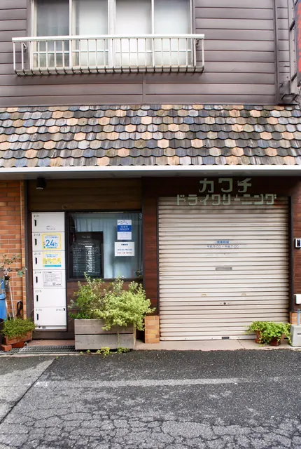 うろこのような屋根と、「カワチドライクリーニング」の文字が残る店先