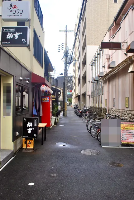 黒い「かず」の看板と、自転車がずらりと並ぶ細い路地