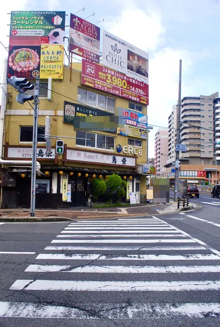 たくさんの看板がついた黄色いビルと、手前の大きな横断歩道