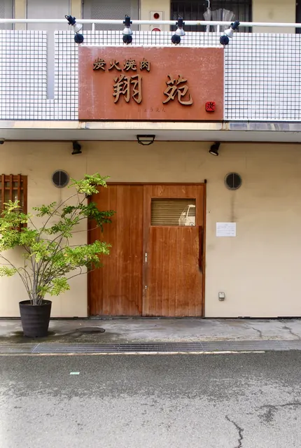 「炭火焼肉 翔苑」の看板と、大きな木の扉の店先