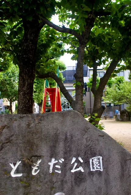 「ともだ公園」と刻まれた大きな石と、木陰の広場