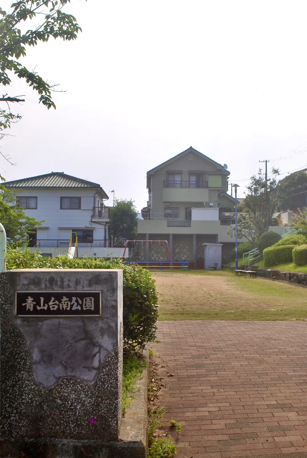 「青山台南公園」の銘板と、ブランコのある広場