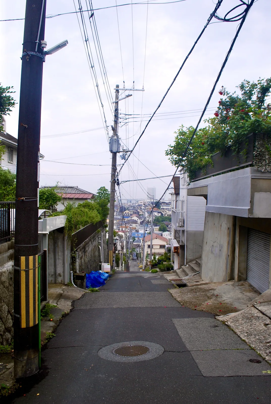 家々のあいだを、遠くの町並みへまっすぐ下る急な坂道