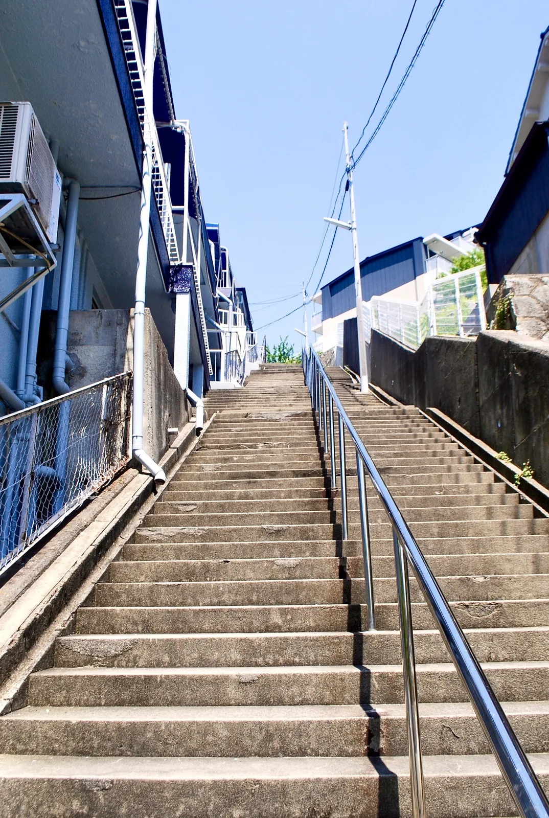 建物の脇を、青空へ向かってまっすぐ上る長い石段