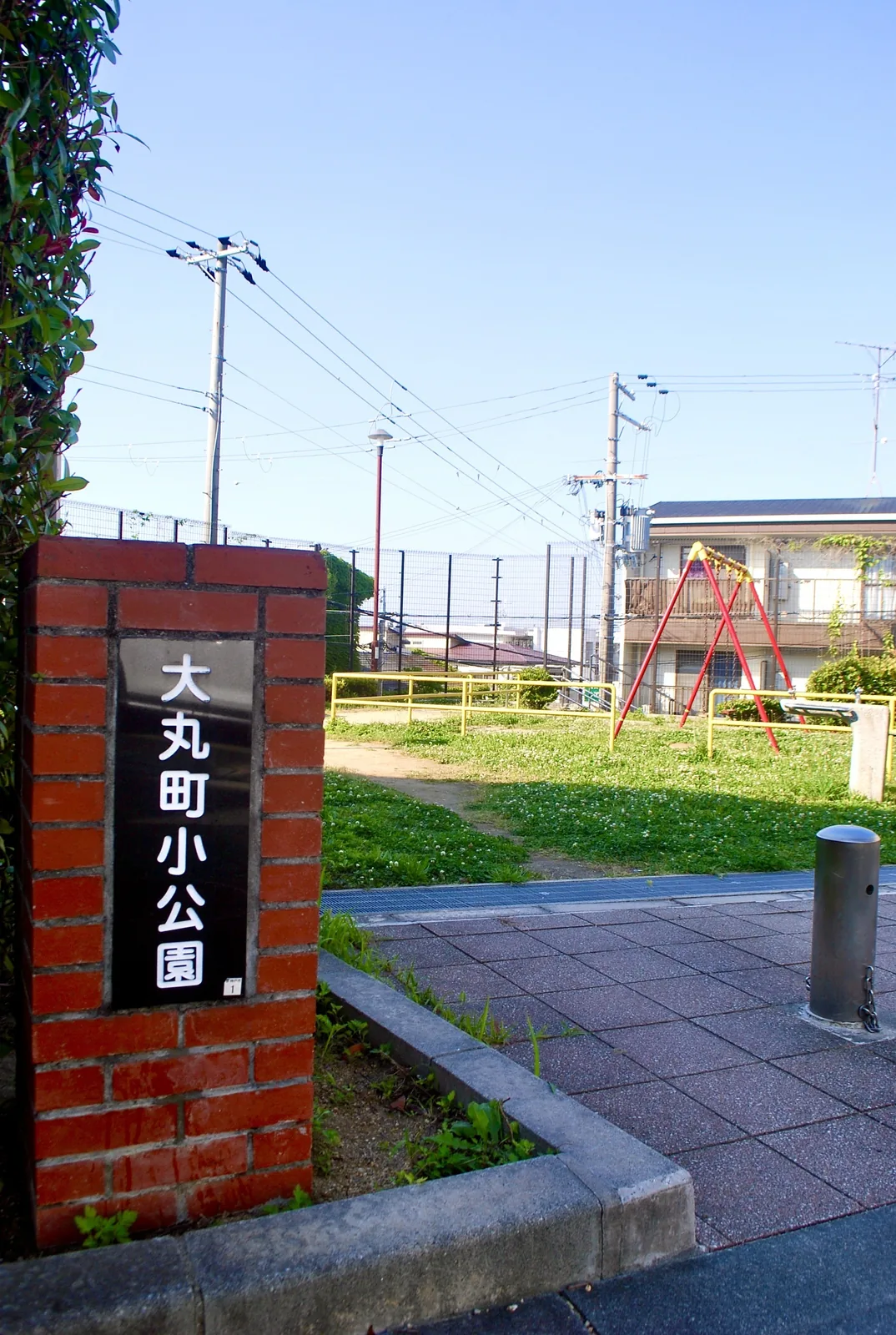 レンガの門柱の奥に、ブランコの見える小さな公園