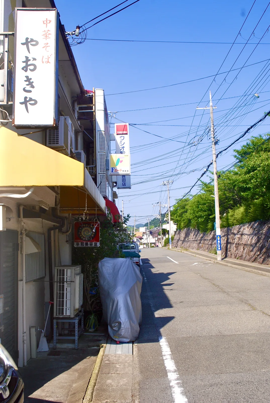 中華そばの縦長の看板と、黄色い日よけのある通り