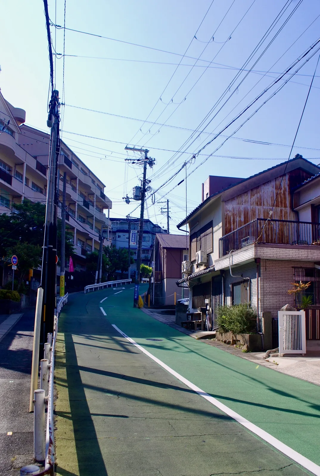緑色の自転車レーンが、家々のあいだを上っていく坂道