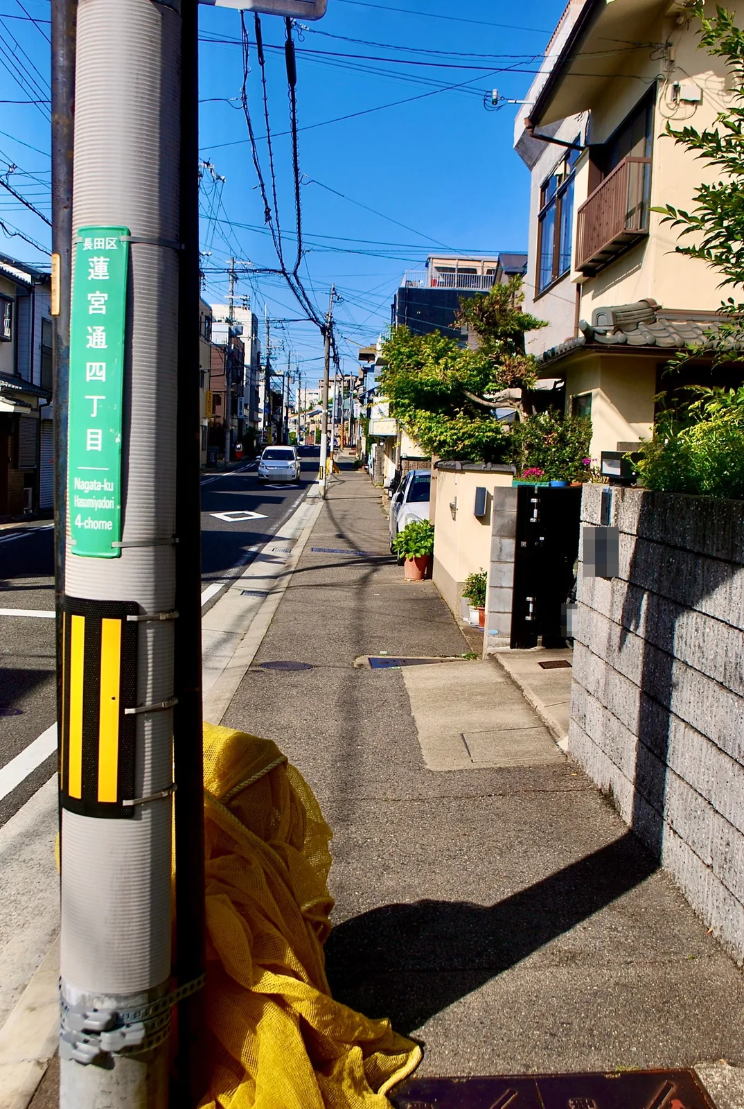 蓮宮通四丁目の表示のある電柱と、奥へ続く歩道