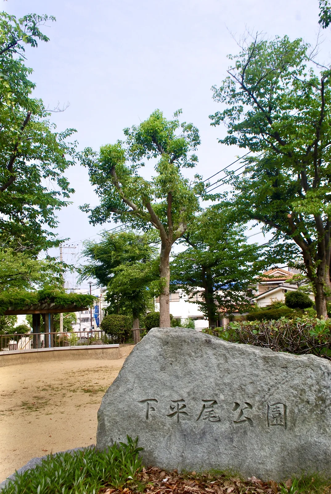 「下平尾公園」と刻まれた大きな石と、木々に囲まれた広場