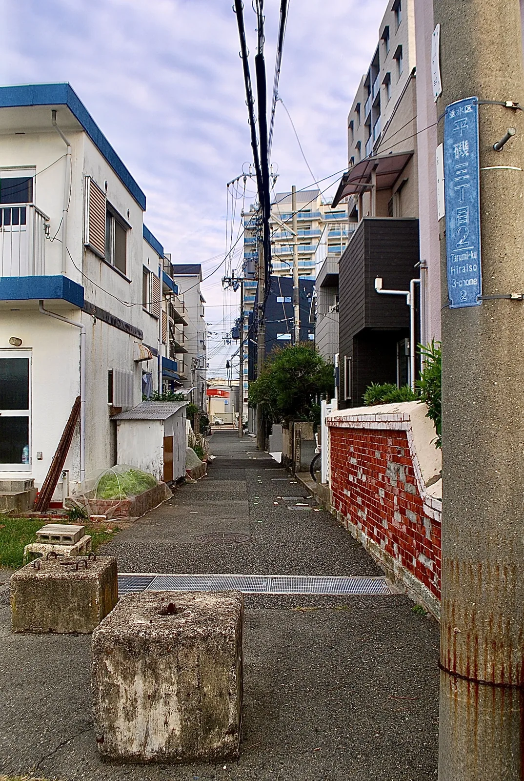 町名表示のある電柱の脇を、奥へ続く細い路地