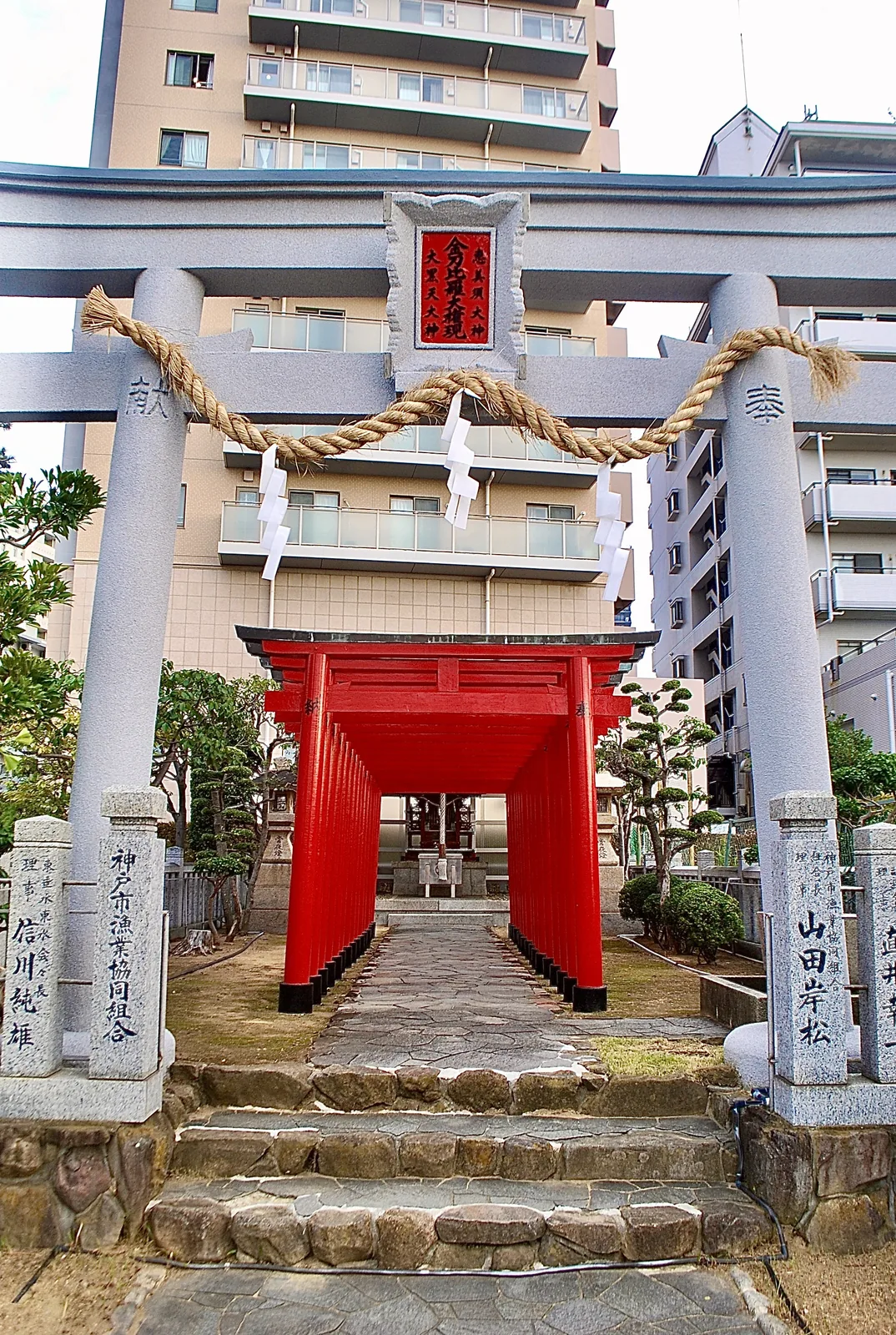 しめ縄の掛かる石の鳥居の奥に、朱色の鳥居とお社が見える風景