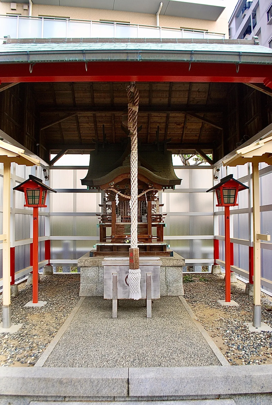赤い提灯が両脇に立つ、屋根の下の小さなお社