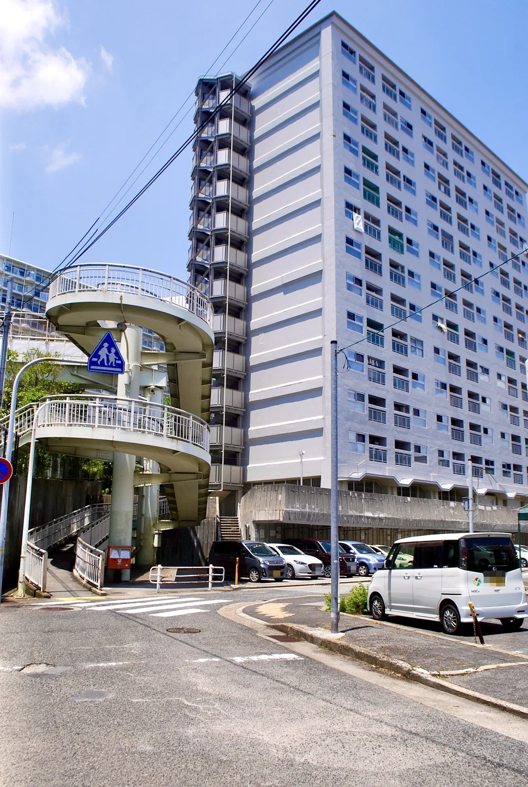 らせん階段のついた歩道橋と、その奥にそびえる団地