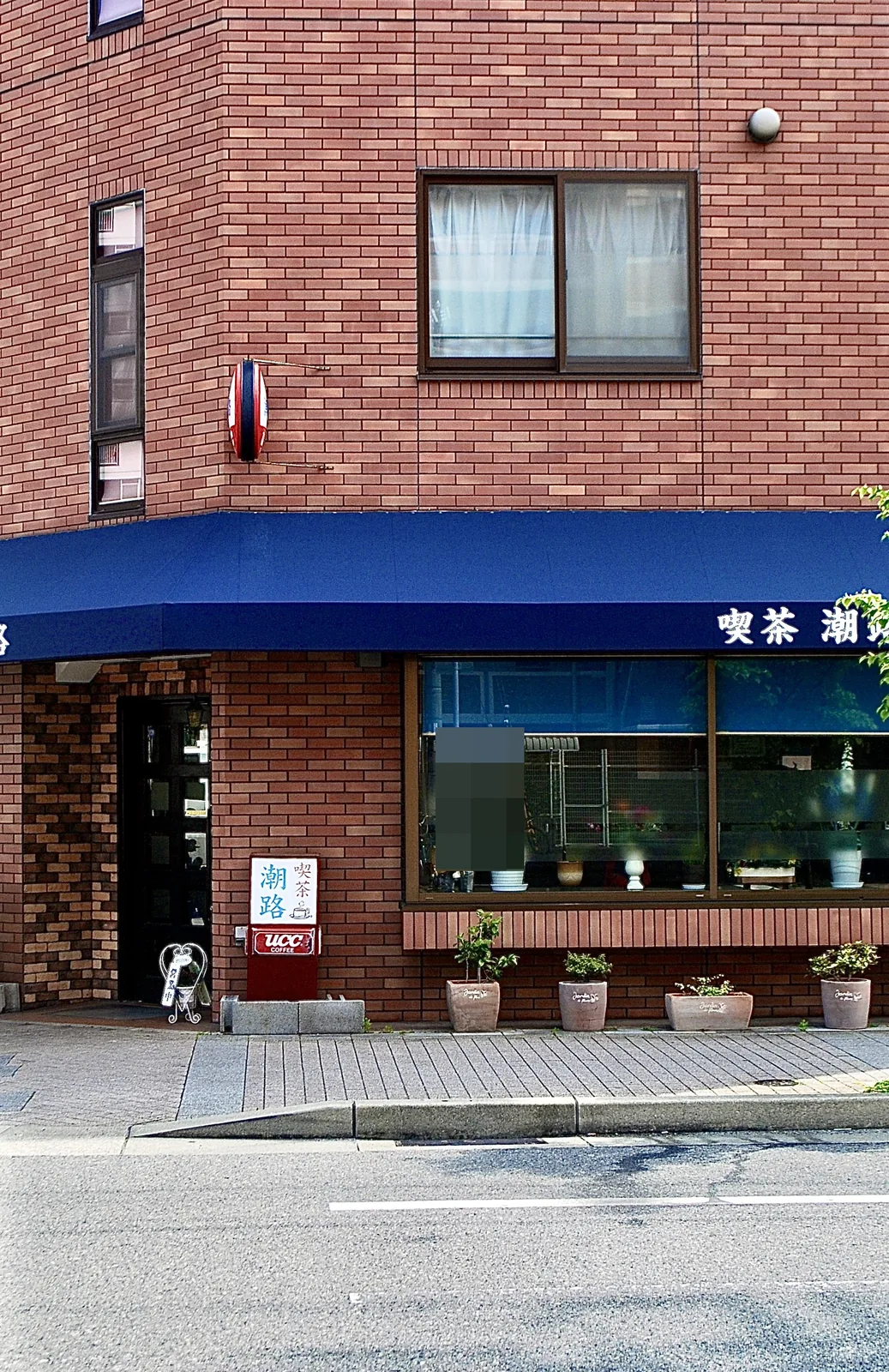 青い日よけとレンガの壁の、角の喫茶店