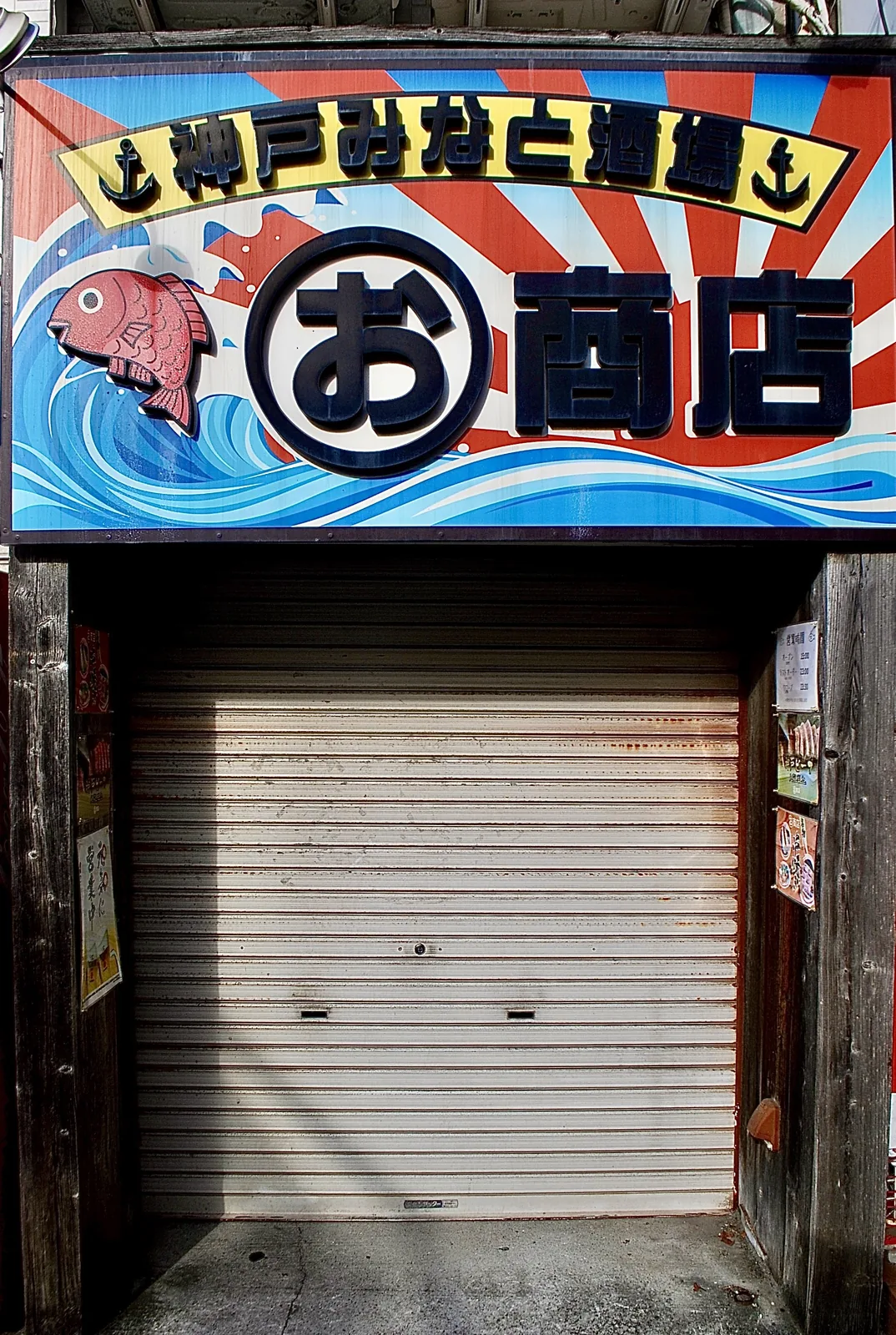 波と魚が描かれた大きな看板の下の、閉まったシャッター