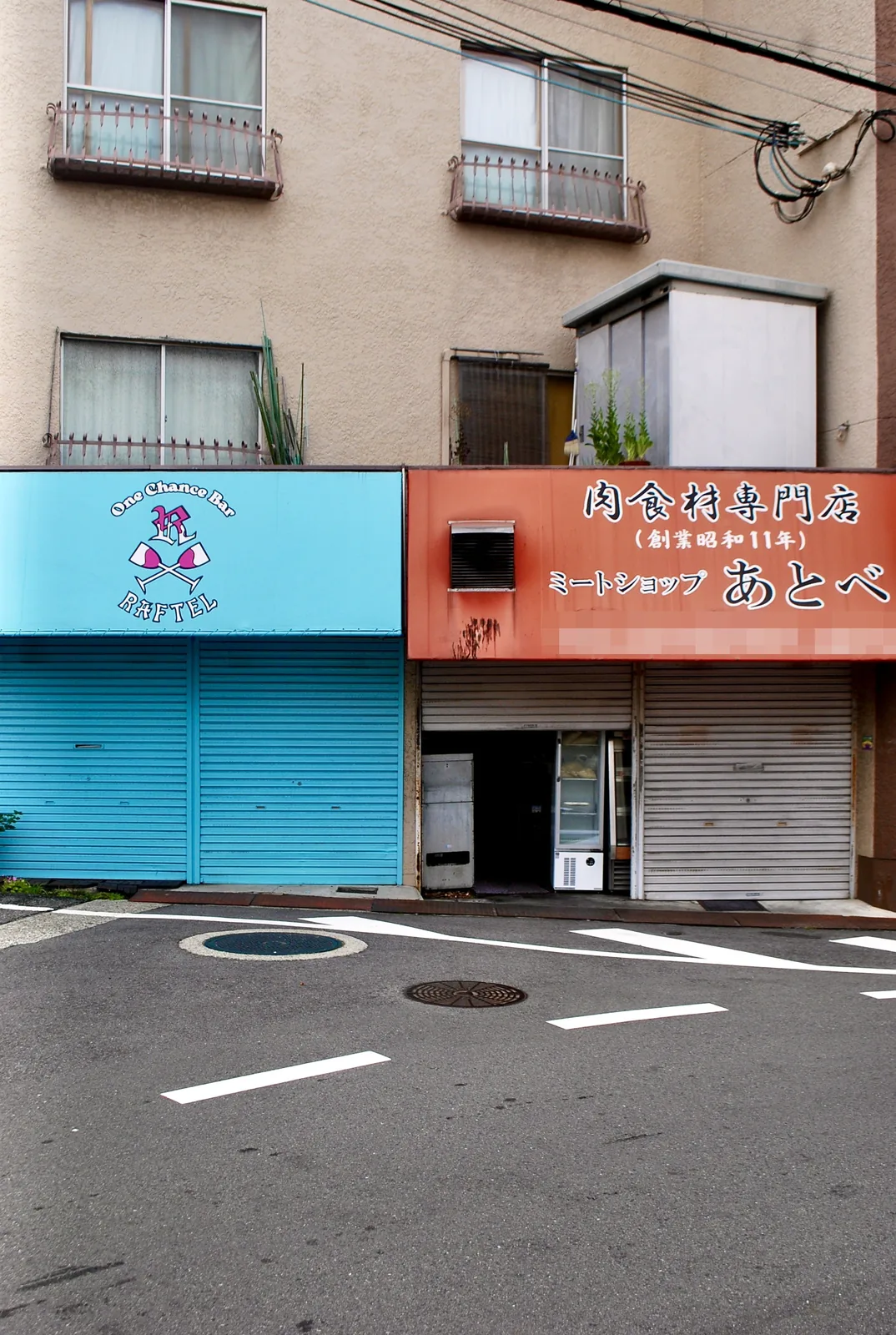 水色とオレンジのシャッターが並ぶ、昭和創業の精肉店の店先