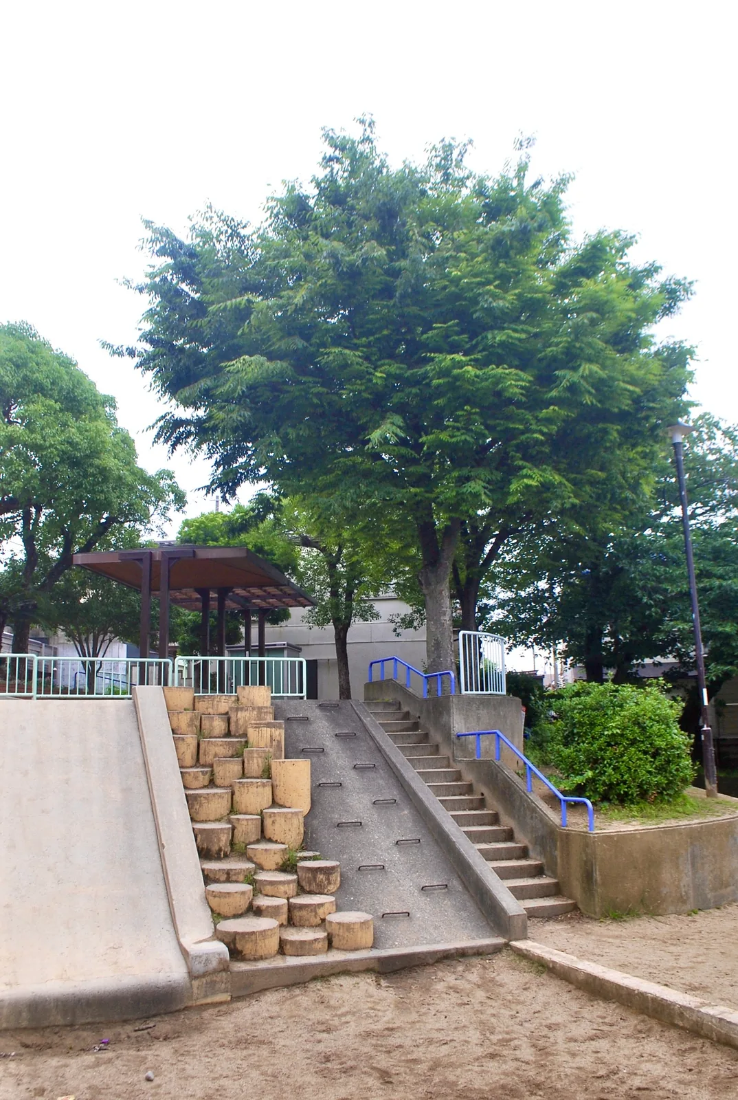 丸太を並べた階段とすべり台、あずまやのある公園