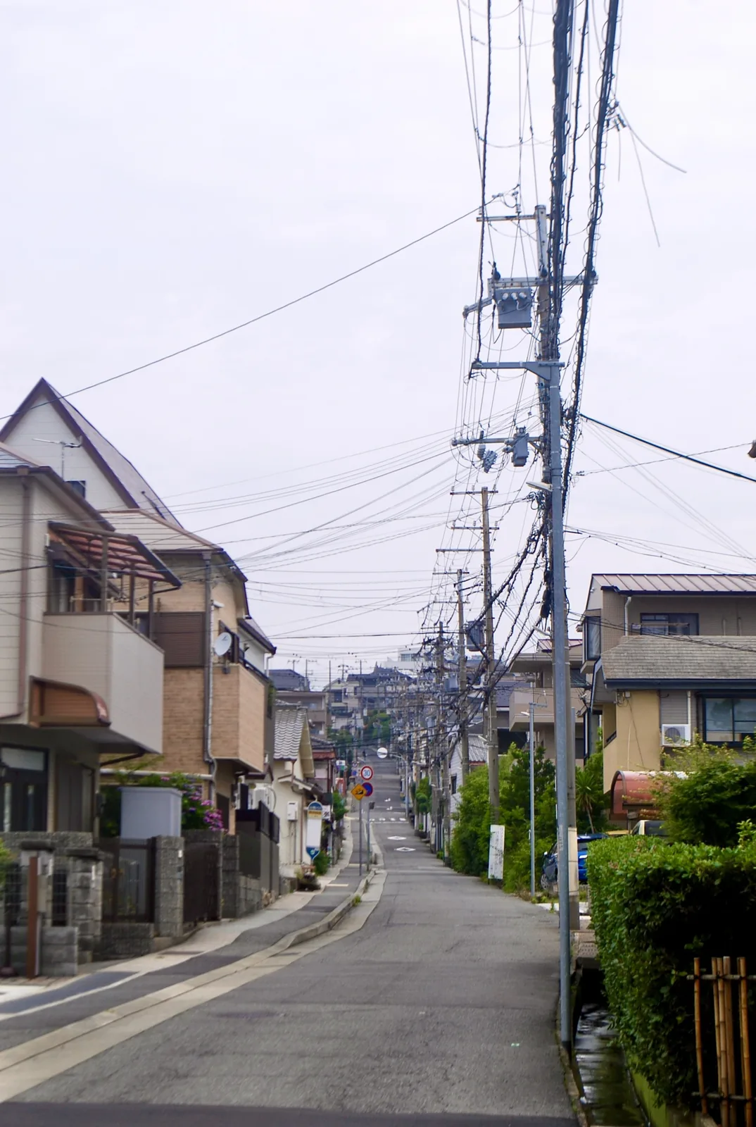 電柱と電線がずらりと並び、遠くまで続く上り坂