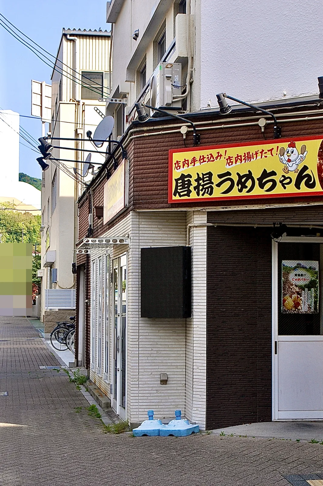 黄色い看板の「唐揚うめちゃん」と、並木の続く広い歩道