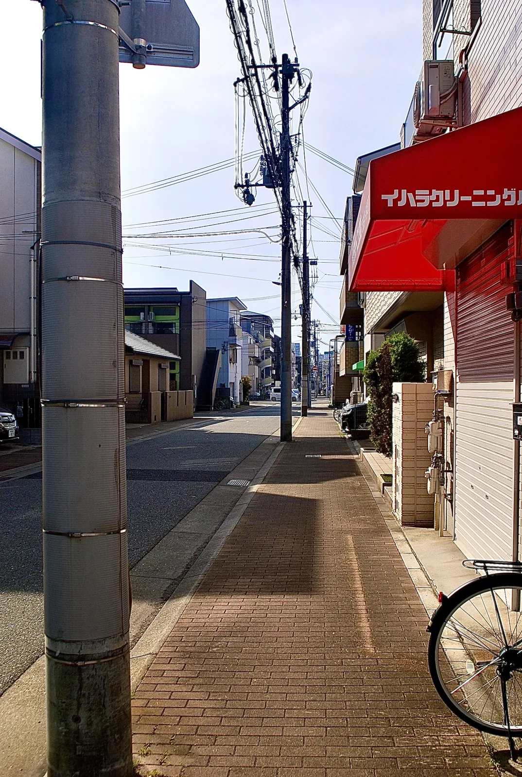赤い日よけのクリーニング店から、まっすぐ続く歩道