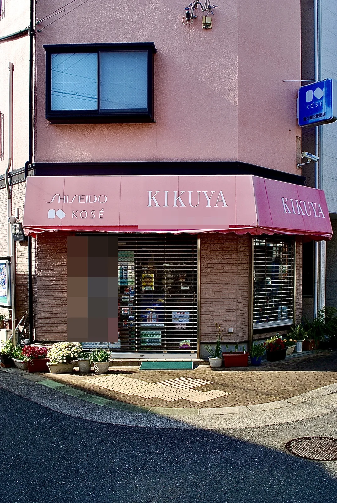 ピンクの日よけに「SHISEIDO」「KOSÉ」と書かれた化粧品店の角