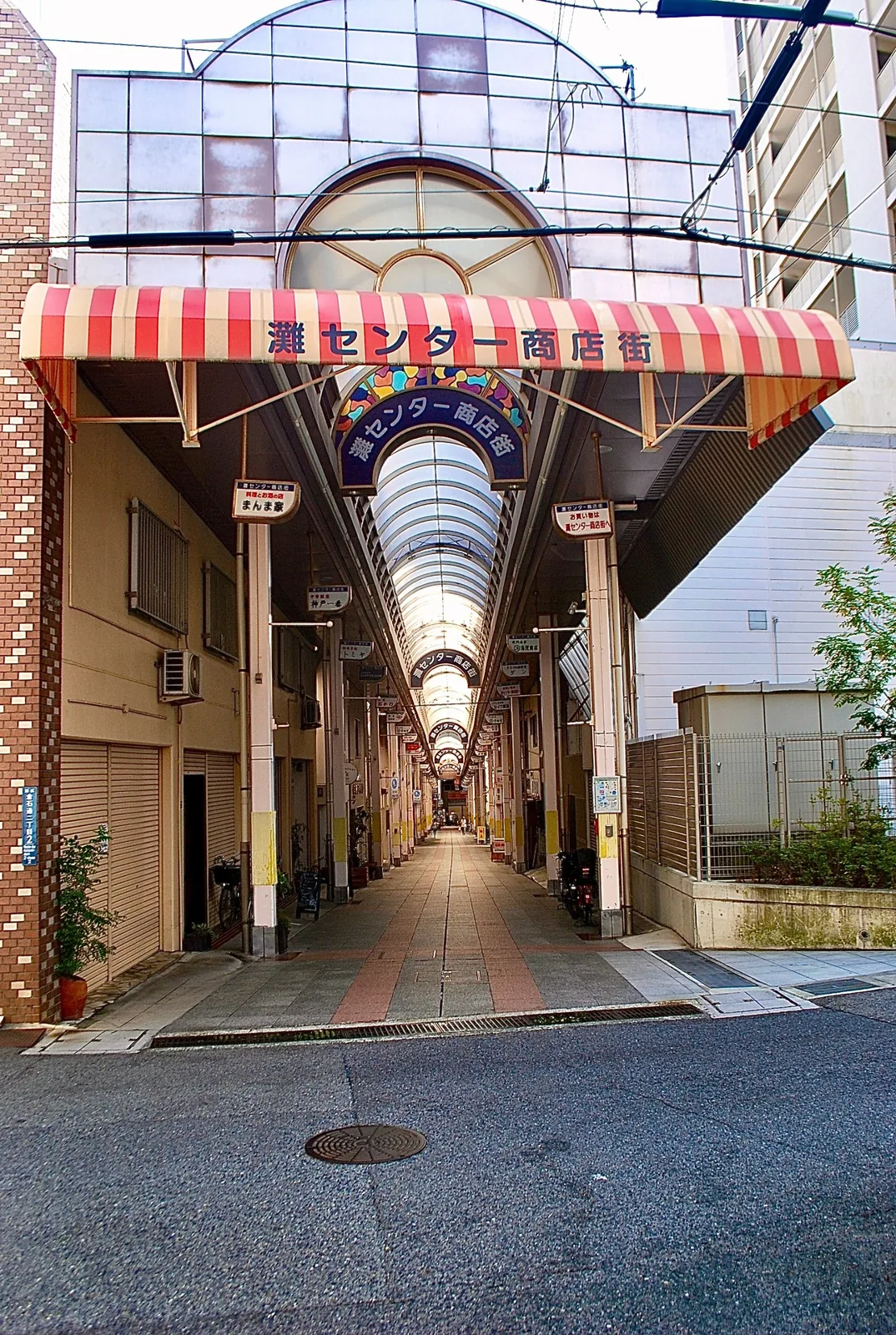 赤白の縞模様の日よけがかかる、商店街のアーケードの入口