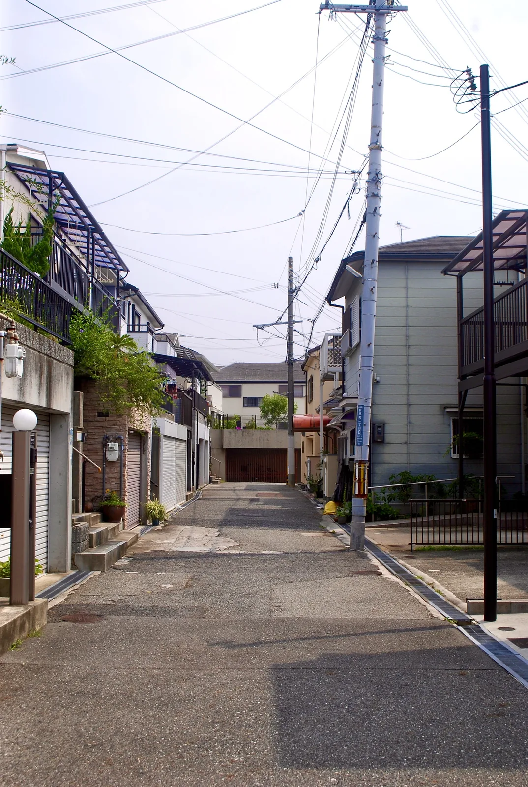 家々とガレージのあいだを、奥へ続く静かな住宅街の道