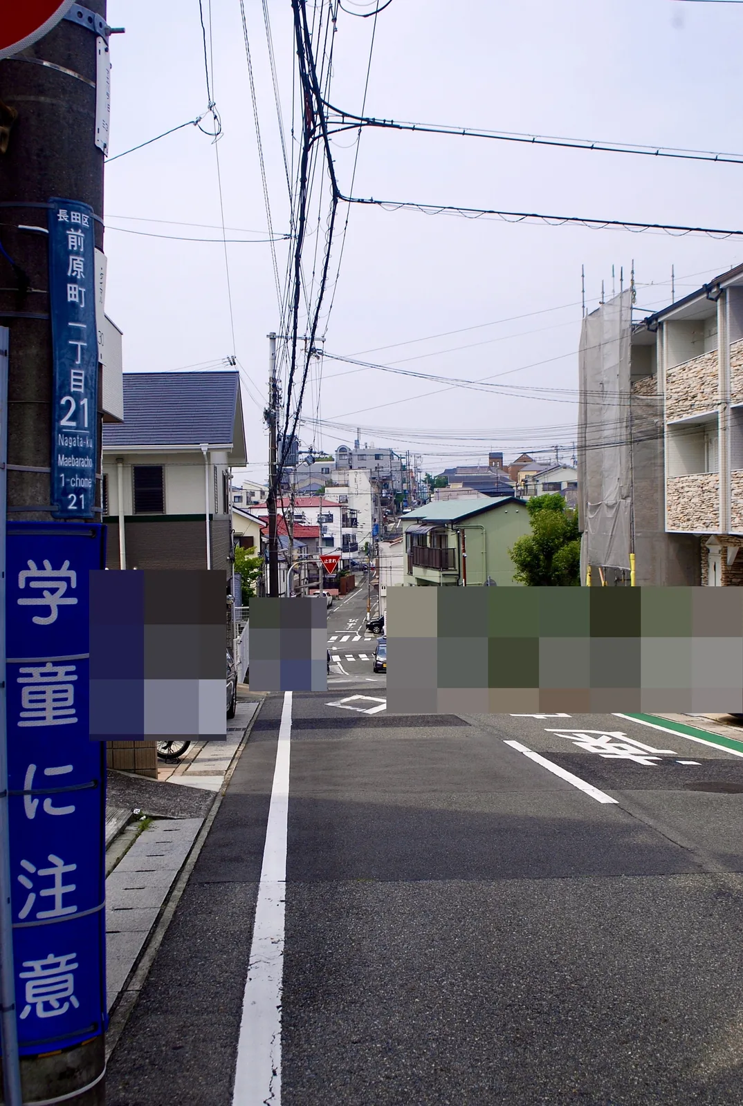 「前原町一丁目」の電柱の先に、坂の下へ続く広い道