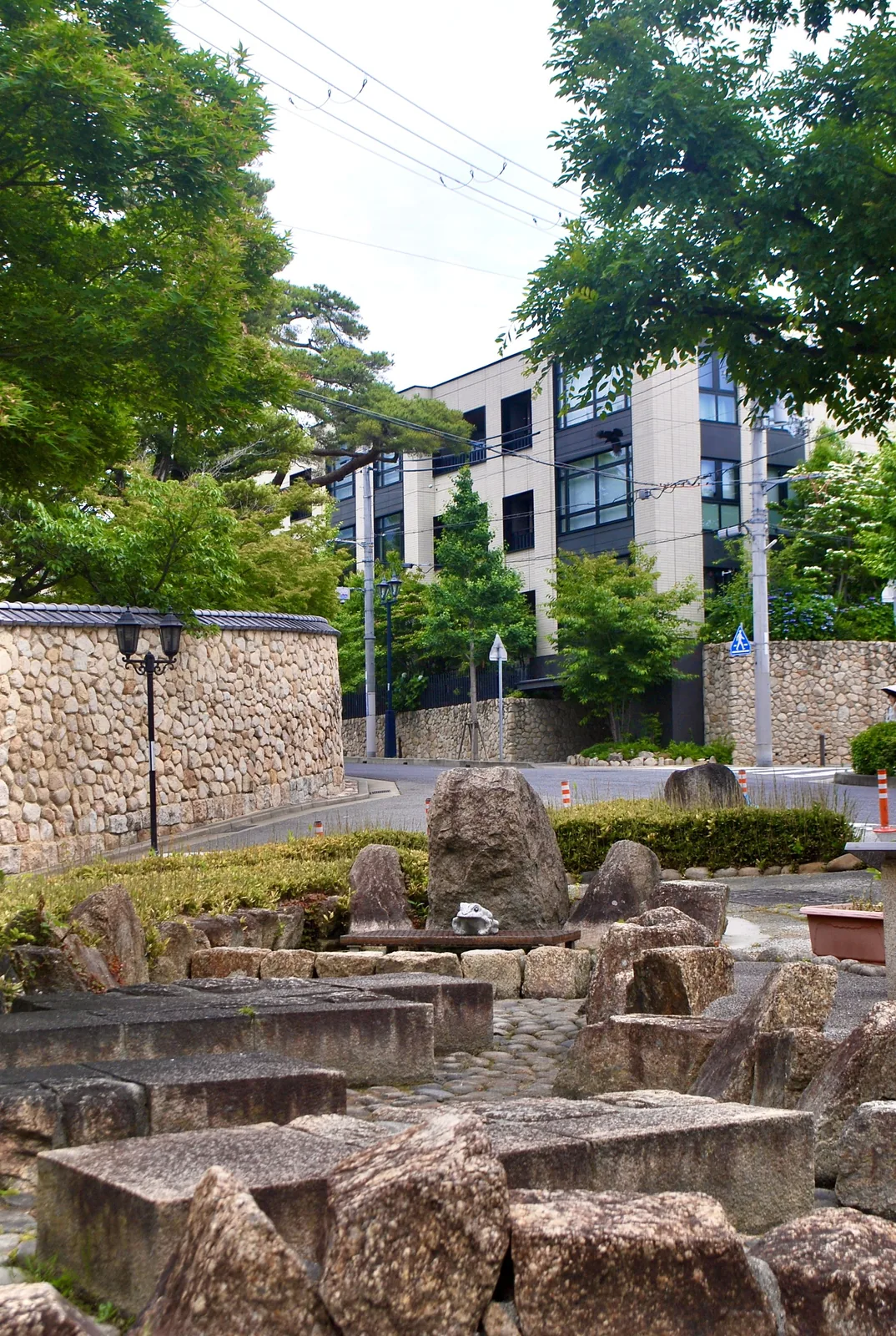 丸い石を積んだ石垣の塀と、石を並べた小さな庭のある交差点