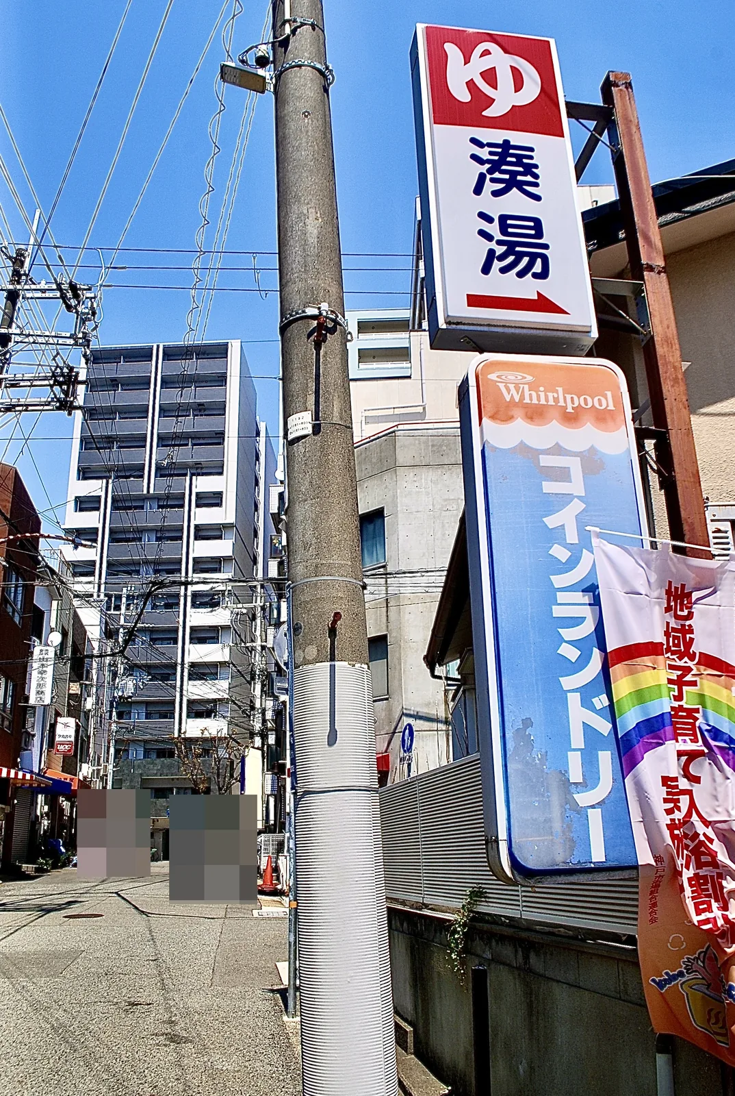 赤い「ゆ」の看板と、コインランドリーの看板が並ぶ通り