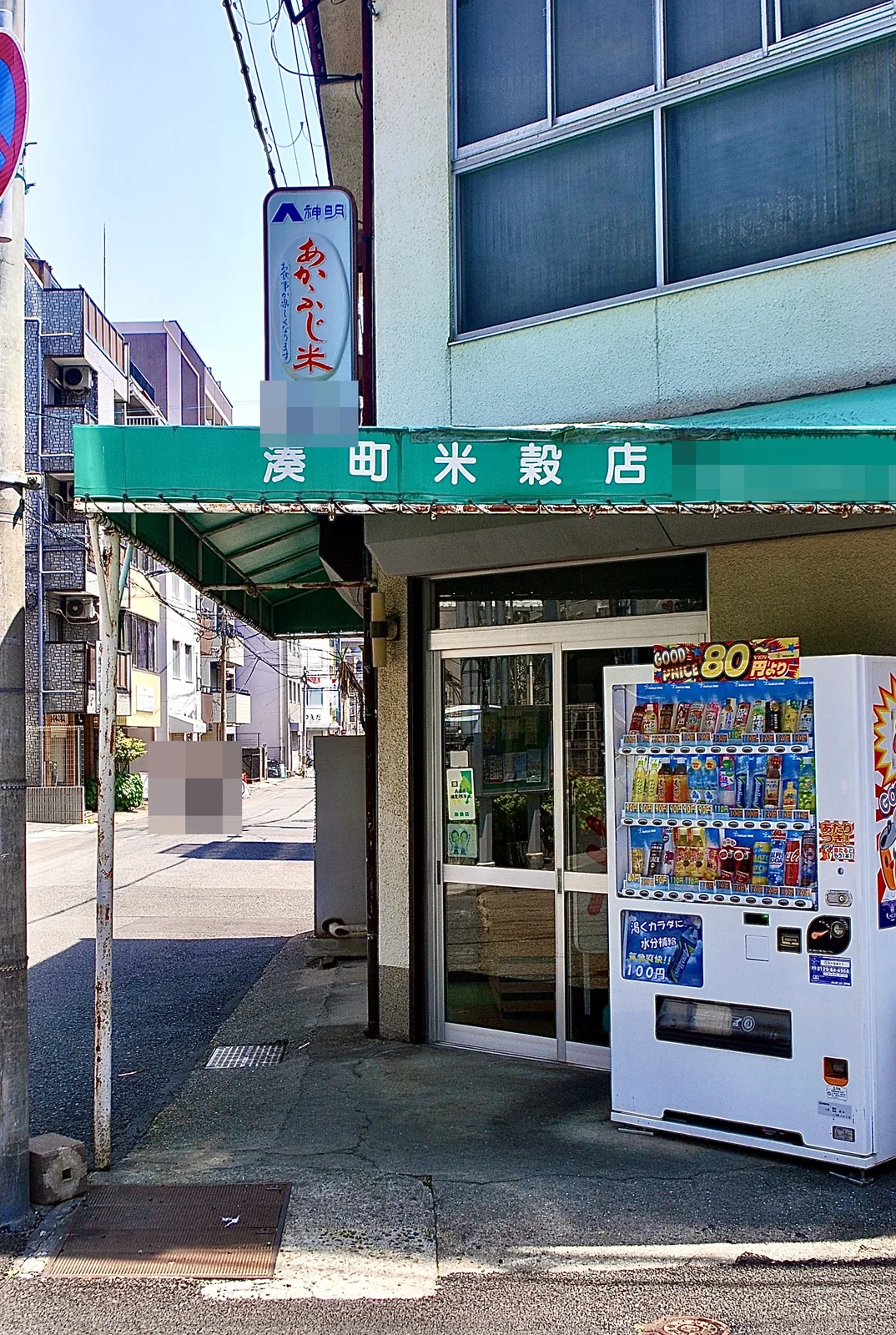 緑の日よけの「湊町米穀店」と、自動販売機のある角