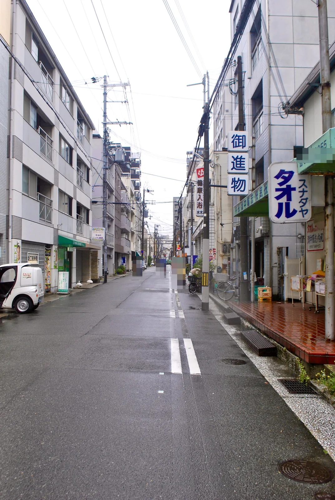 縦長のタオル屋の看板と、奥へ続く下町の通り