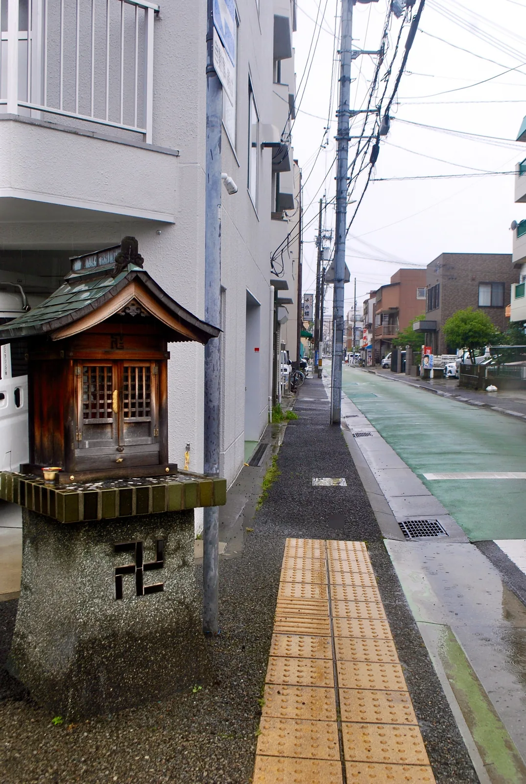 新しい家と古い家が並ぶ、雨の日の住宅街の通り