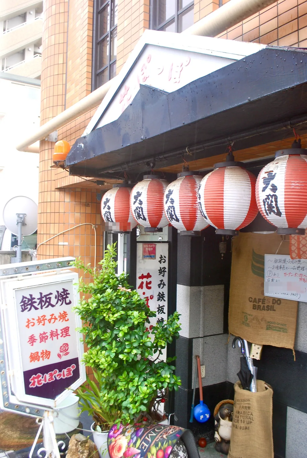 「鉄板焼」の看板と提灯、植木の並ぶ店先
