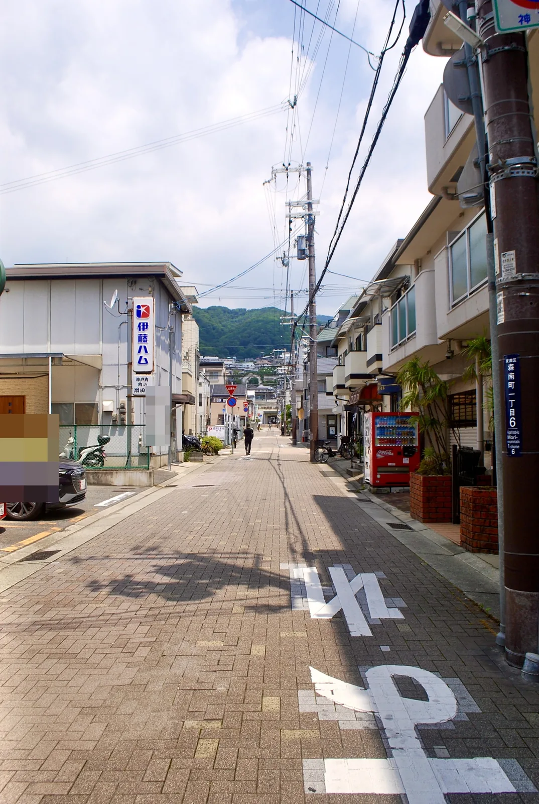 「森南町一丁目」の表示がある電柱と、山へ続く石畳の道