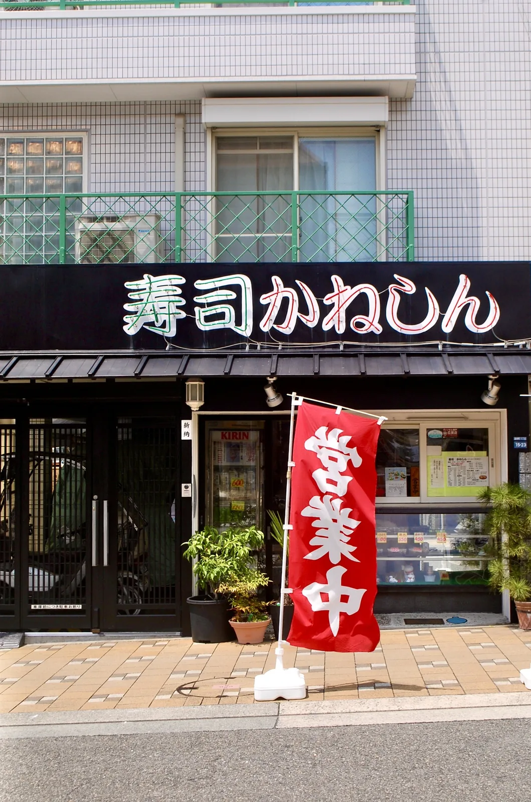 黒い店構えに赤い「営業中」ののぼりが立つ寿司屋