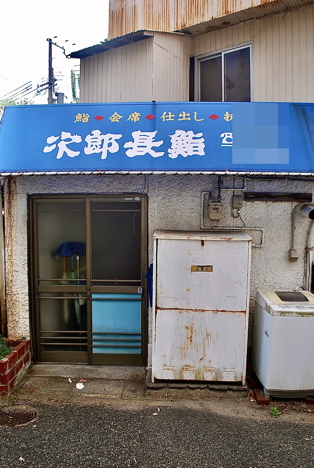 青い日よけに「次郎長鮨」と書かれた店の、裏口の風景