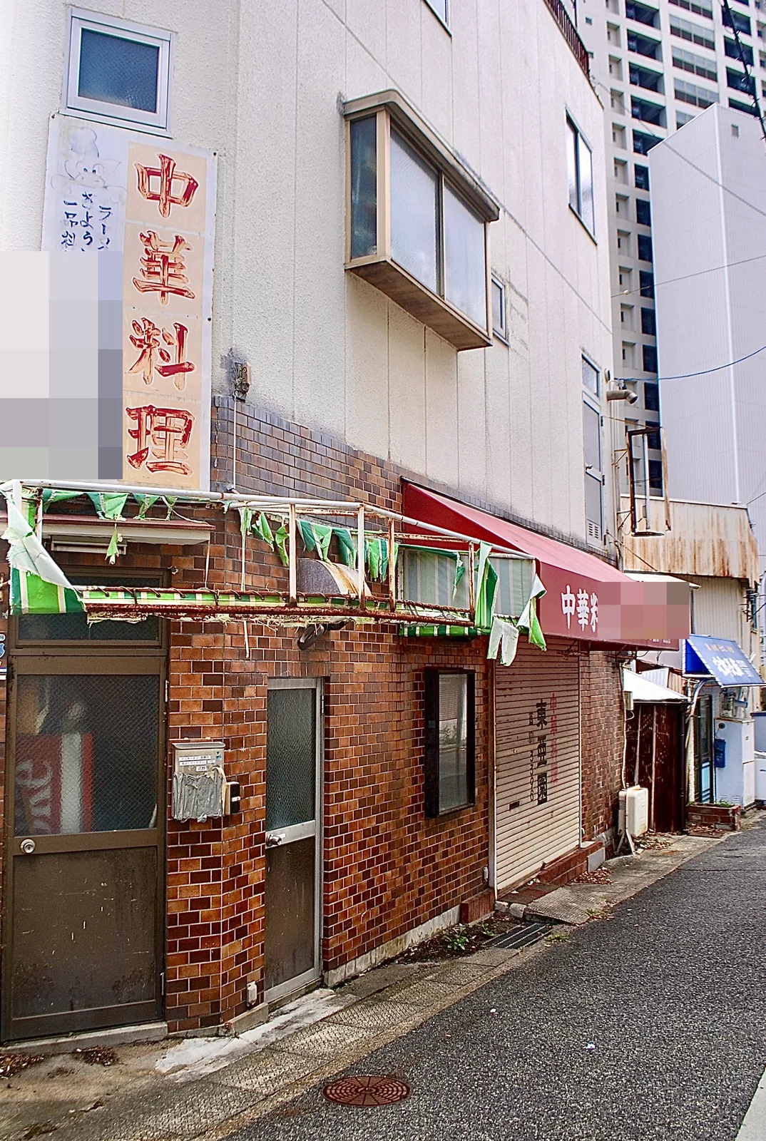 「中華料理」の縦看板と、旗の飾りがさがるレンガ張りの店
