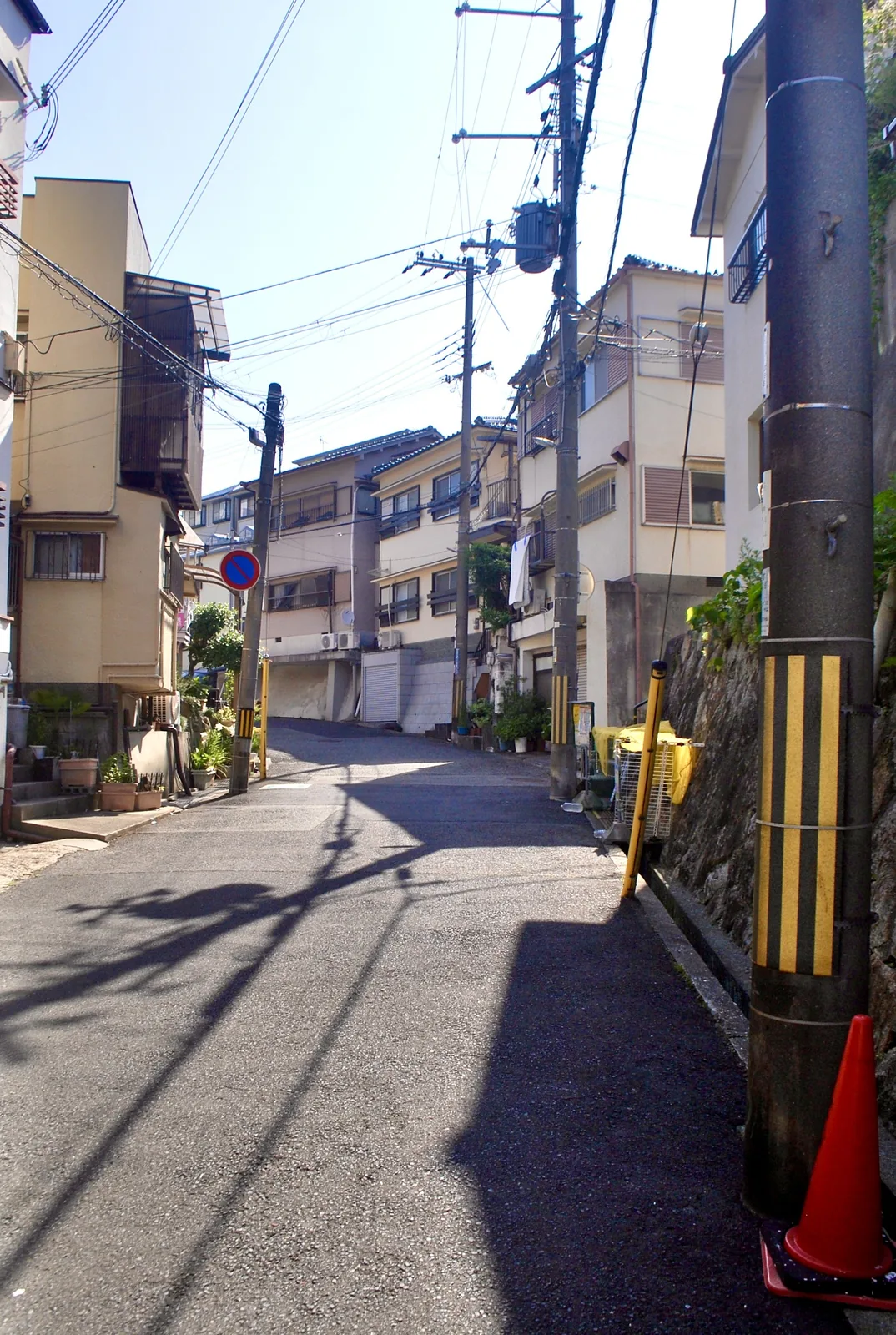電柱の並ぶ、坂の途中の小さな交差点