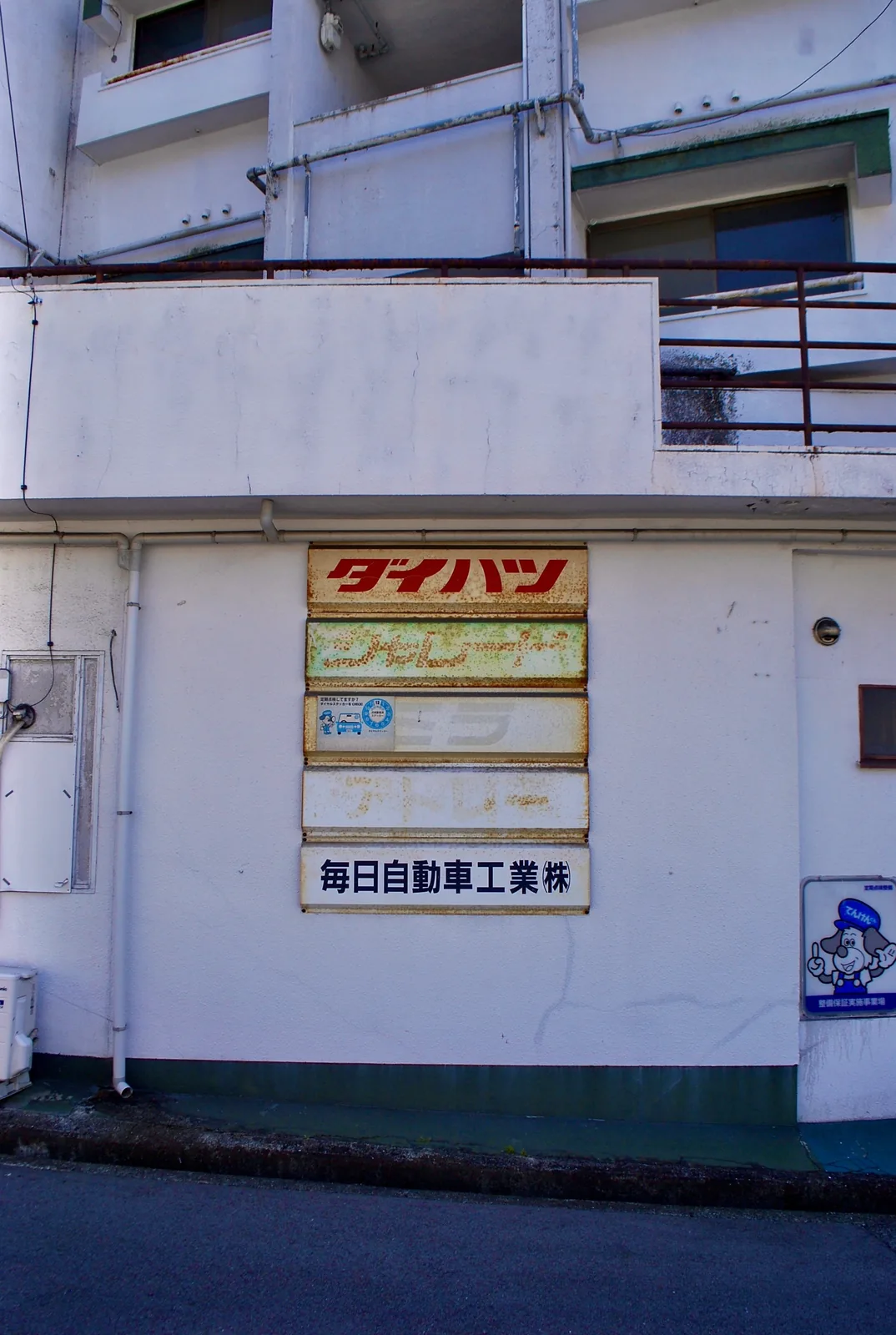 ピンクの喫茶店の看板の先に、奥へ続く坂の通り