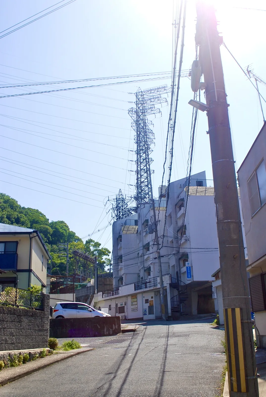 坂の上の交差点の奥に、大きな鉄塔がそびえる風景