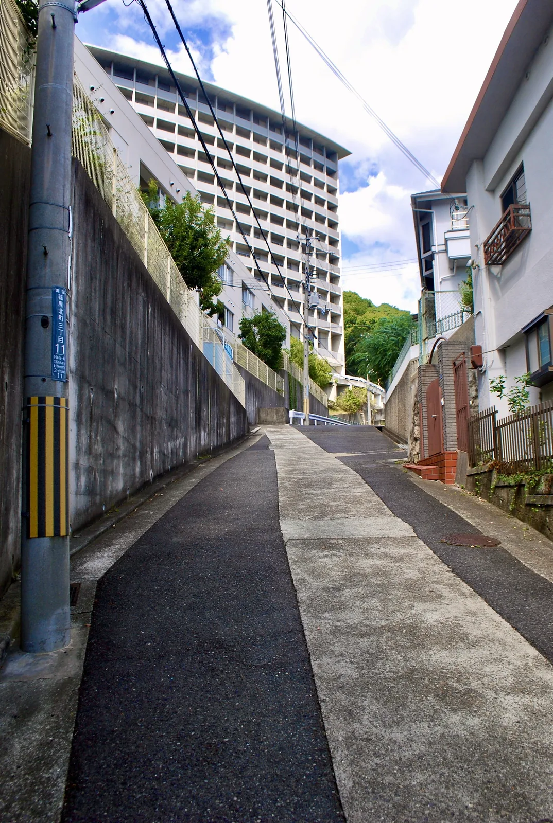 高い壁と大きな集合住宅のあいだを上っていく坂道