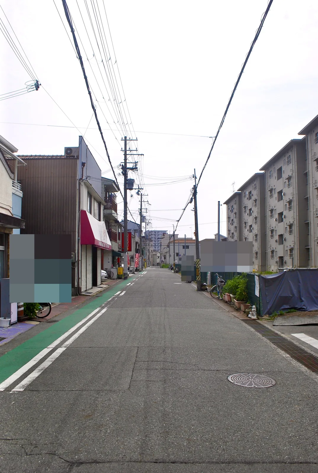 赤いひさしの店と団地のあいだを、まっすぐ続く通り
