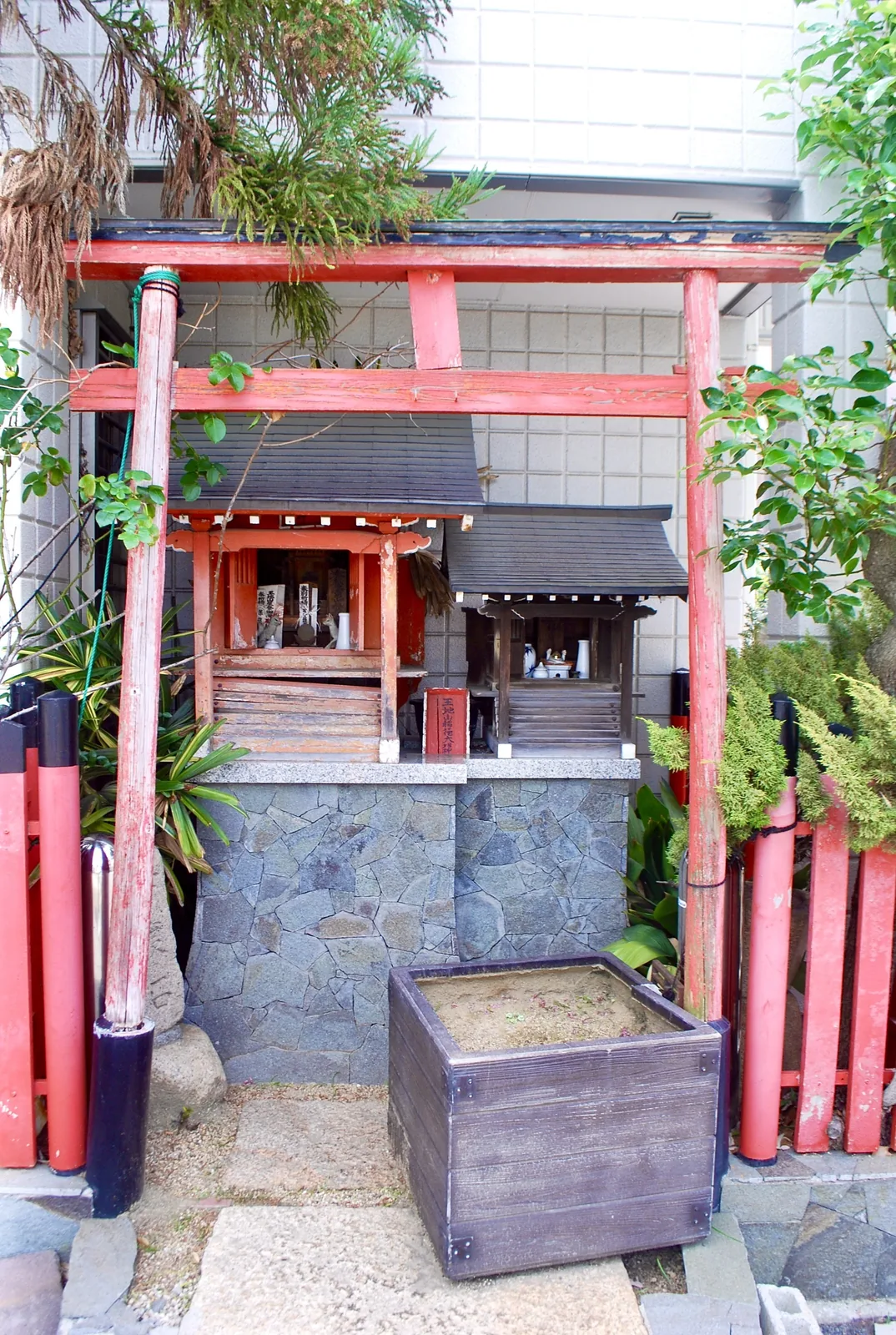建物のあいだにたたずむ、赤い鳥居の小さなお社