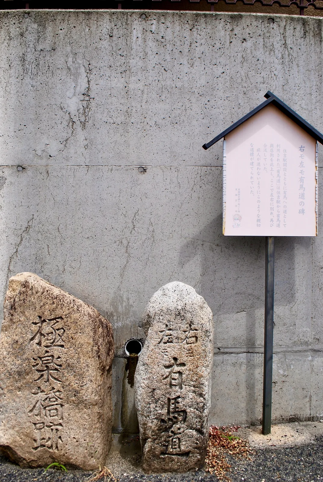 「有馬道」と刻まれた古い石の道しるべと、案内の看板