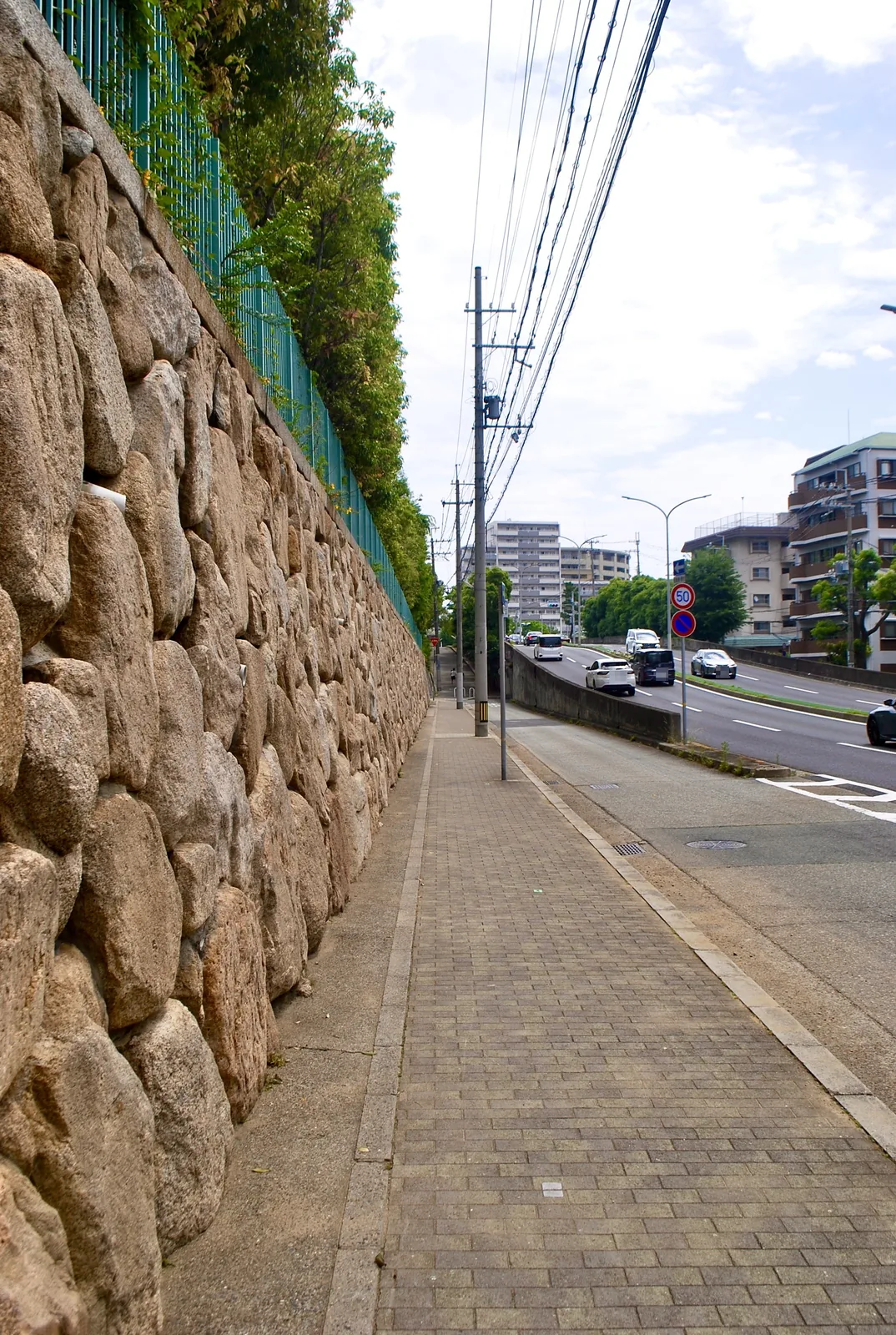 大きな石を積んだ石垣に沿って、まっすぐ続く歩道