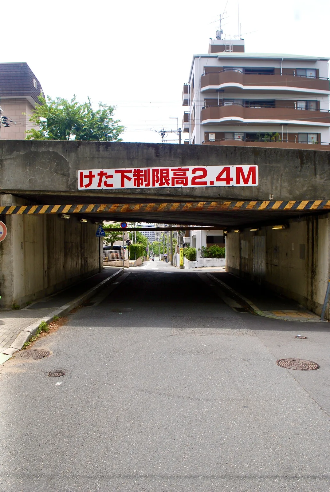 「けた下制限高2.4M」の文字のある、高架下をくぐる道